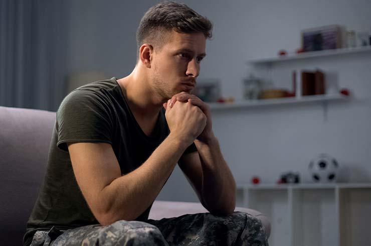 military man sitting on a couch struggling with ptsd and addiction