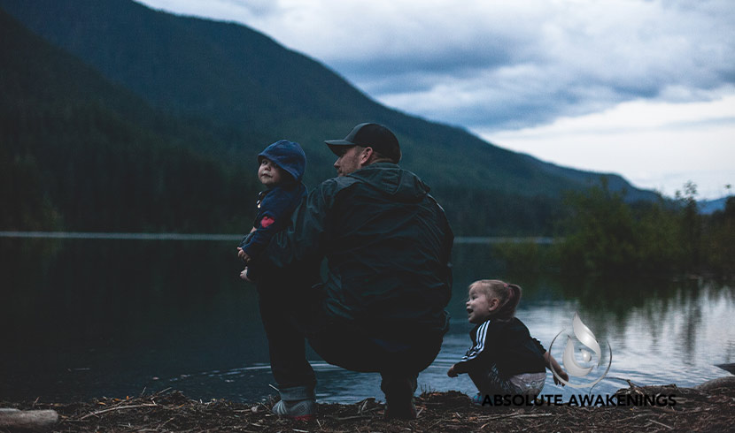 man enjoying time with his two children at a lake in the mountains