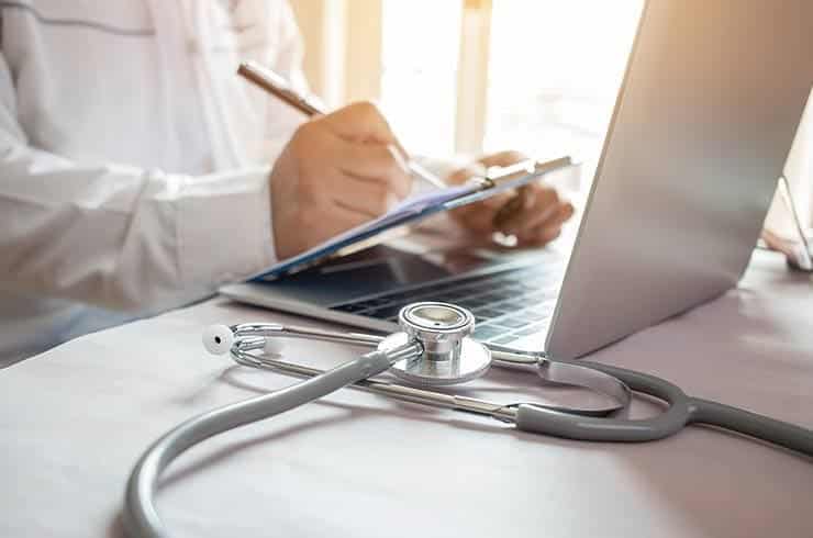doctor sitting in front of his laptop making notes on a patient's medical detox for benzodiazepines