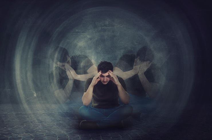 man suffering from schizophrenia in a dark environment with multiple versions of himself in the background