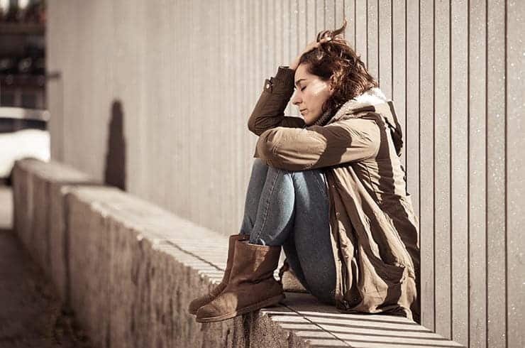 distraught woman sitting outside struggling with drug abuse