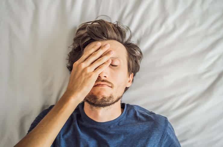 man laying in bed tired from adderall withdrawal
