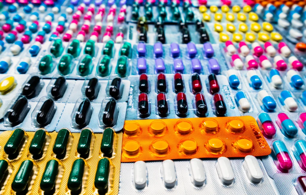 Assorted capsules and tablets in colorful blister packs, top view